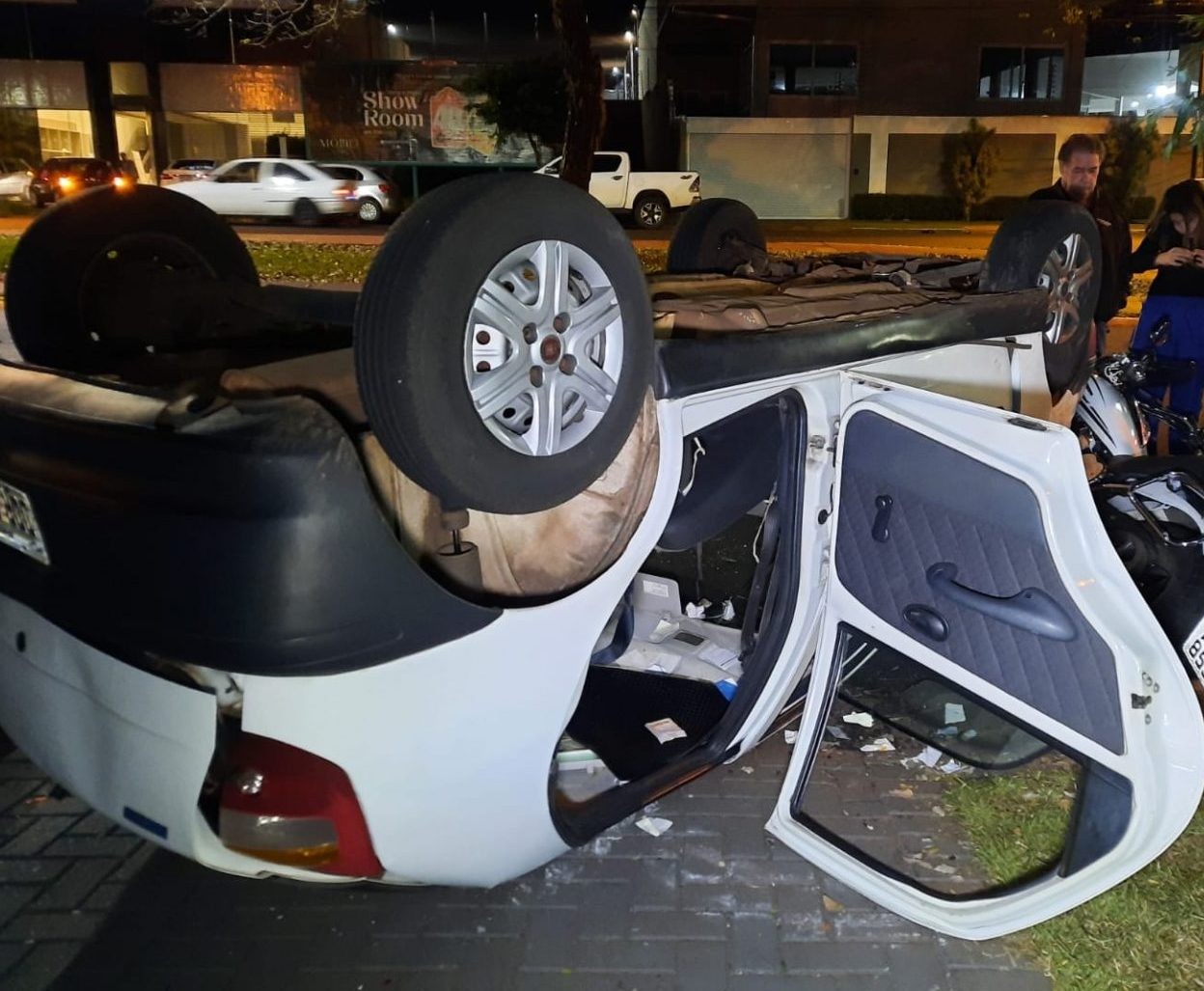Carro capota, cai em cima de moto e motorista é retirado em meio aos estilhaços, em Maringá