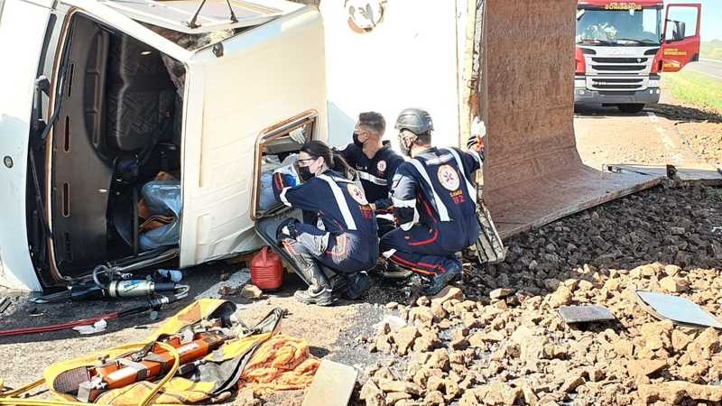 Caminhão carregado com cascalho tomba na PR-323 e motorista fica preso na cabine